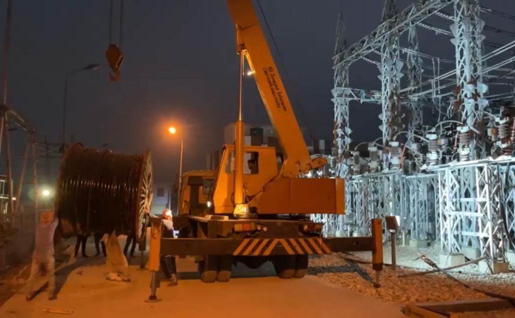 Crane lifting a cable drum at night