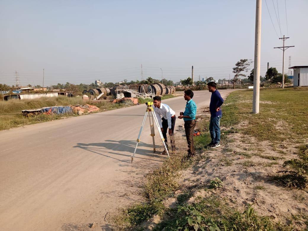 Surveyors taking levels along a cable route with cable drums in the background
